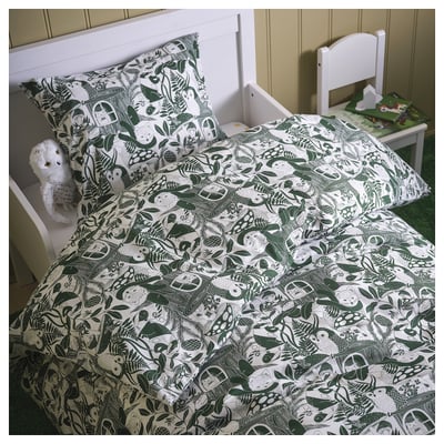 A single bed with SKOGSDUVA duvet, woodland prints, white headboard, chair, and stuffed toy. Cosy forest-themed kids room.