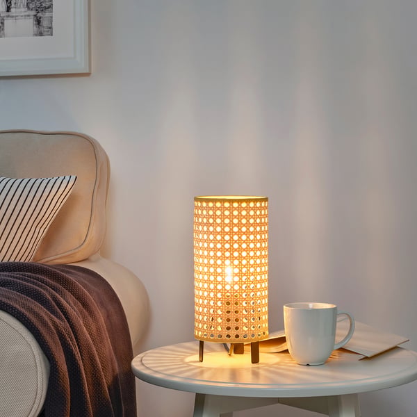 Cosy living room with armchair, blanket, side table, lamp, and wall art.