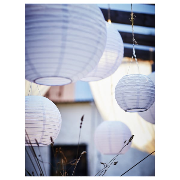 Purple solar lanterns hang outdoor with lighted bulbs.