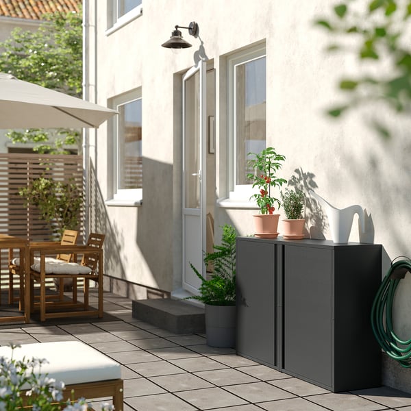 Modern balcony storage cabinet with potted plants, furniture, and building.