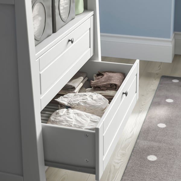 Open white drawer unit with neatly folded baby clothes, part of a versatile changing table and storage solution.