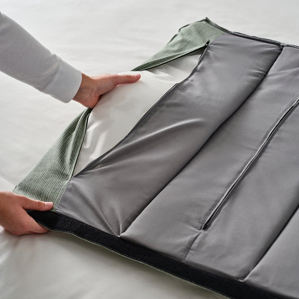 Image shows hands adjusting an upholstered bed frame with a padded headboard, highlighting easy access and storage space underneath.
