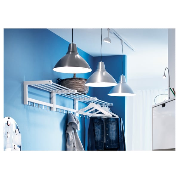 Blue TJUSIG rack on wall holds clothes & basket with sweater. Two silver pendant lamps and a green-shaded white lamp.