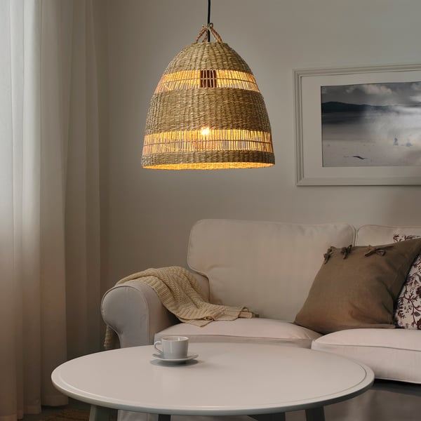 Cosy living room with TORARED sedge pendant lamp, warm light, beige sofa, seascape art, coffee table, inviting atmosphere.