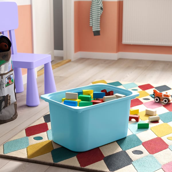 A colourful toy bin on a play mat with scattered blocks suggests a childs play area with accessible and organised storage.