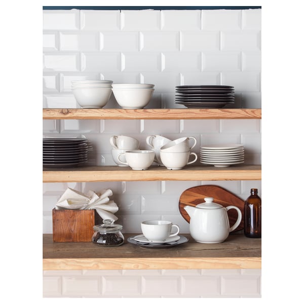 Wooden shelves against white brick wall holding VARDAGEN white dinnerware, including plates, bowls, cups, and jug.