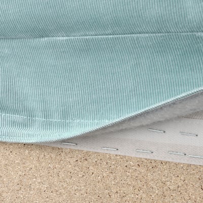Close-up of washable, light blue VIMLE sofa fabric with white stitching, laid on cork surface.