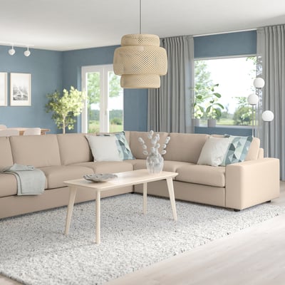 Modern living room with VIMLE sofa, coffee table, grey curtains. Natural light, cosy decor, blue/white pillows, rug, pendant lamp, plants.
