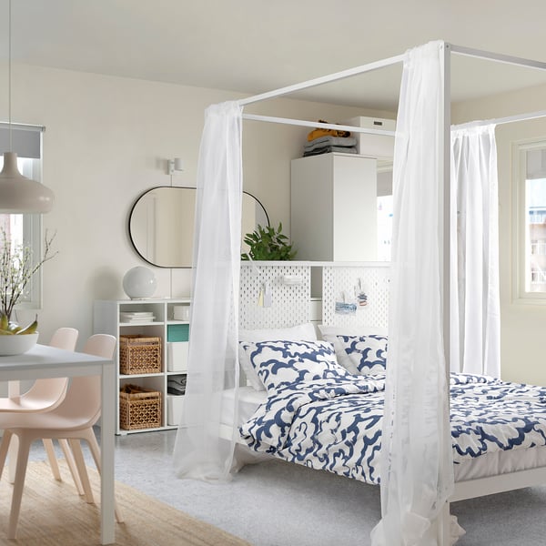 Modern bedroom with VITARNA bed, blue bedding, pegboard, & minimalist decor.
