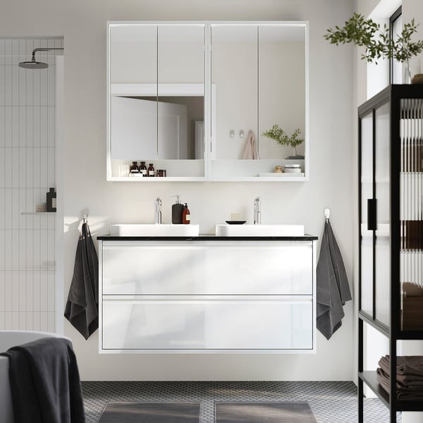Modern white ÄNGSJÖN bathroom vanity with glossy finish, sleek sink, mirrored cabinet, and minimalist shower head.