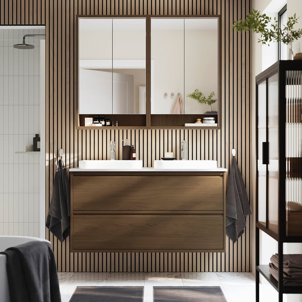 Modern wooden bathroom setup with dual sinks, large mirror, sleek cabinet, and minimalist decor.