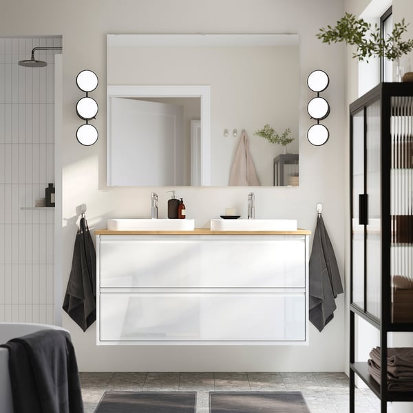 Modern bathroom with ÄNGSJÖN vanity, wooden counter, mirrors, black towels.