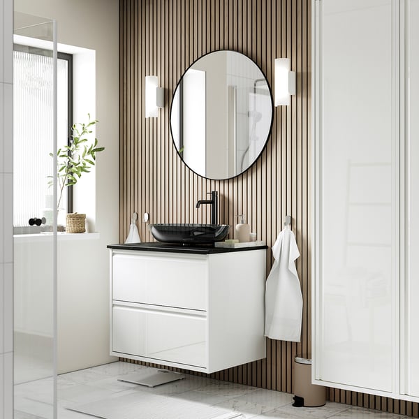 Modern bathroom with white ÄNGSJÖN vanity, glass basin, round mirror, wall-mounted for airy feel.