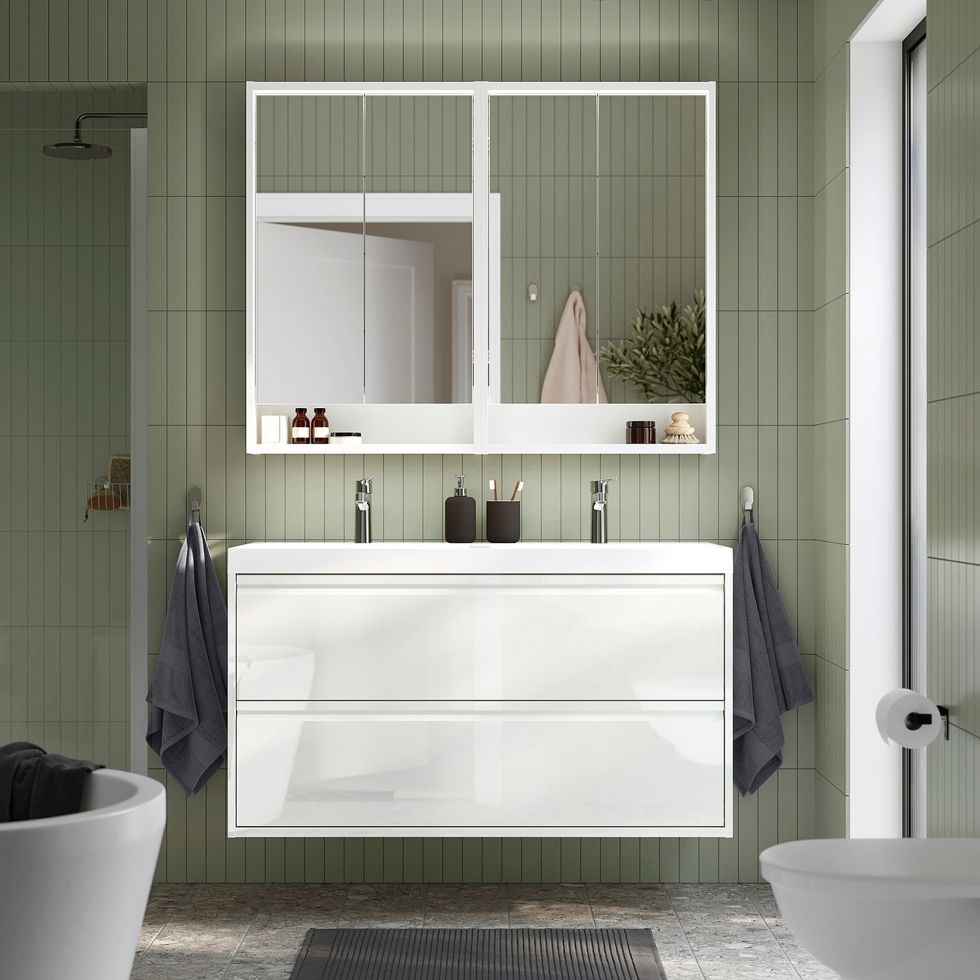Modern bathroom with white ÄNGSJÖN vanity, sleek design, glass doors, minimalist drawer, clean sink, mirror, & towels.