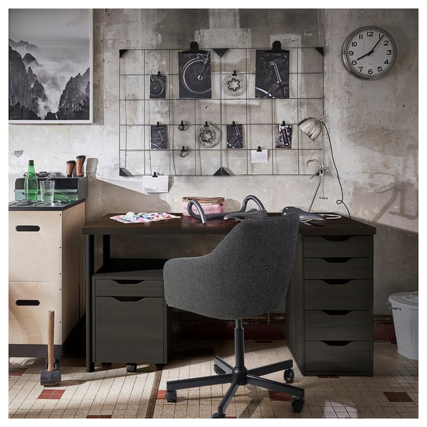 Home office setup with dark wood desk, grey chair, wall clock, and decorative wall art.