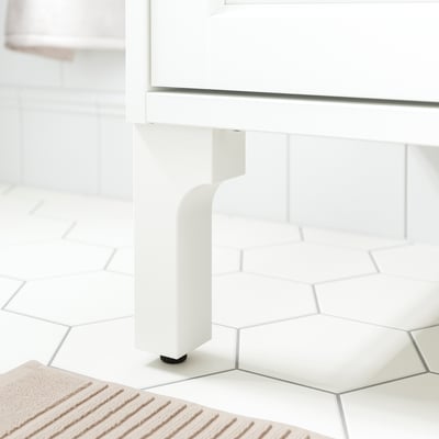White wooden table leg with adjustable foot for stability.