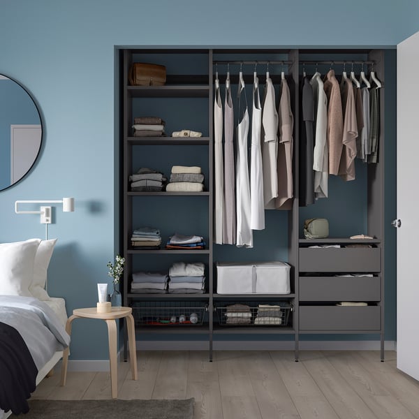 Modern blue AURDAL wardrobe with clothing and shelves, mirror, light, and side table in bedroom.