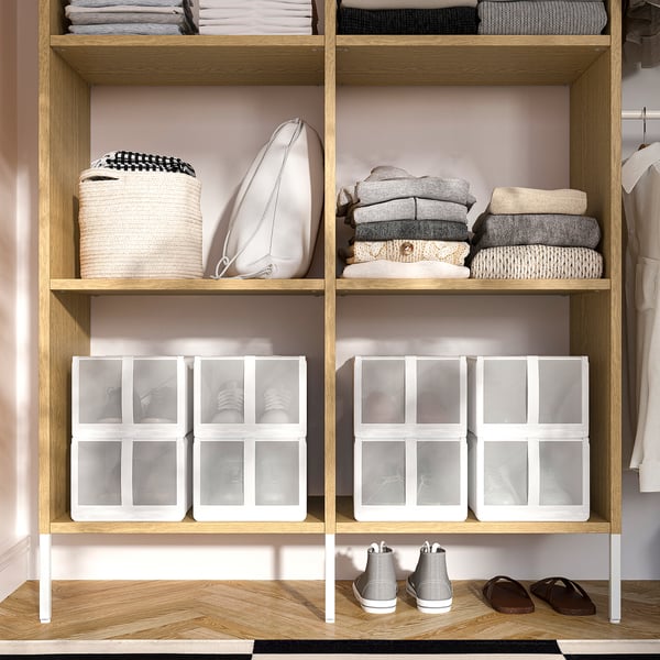Organised closet with wooden shelves holding clothes, shoes, and clear storage boxes.
