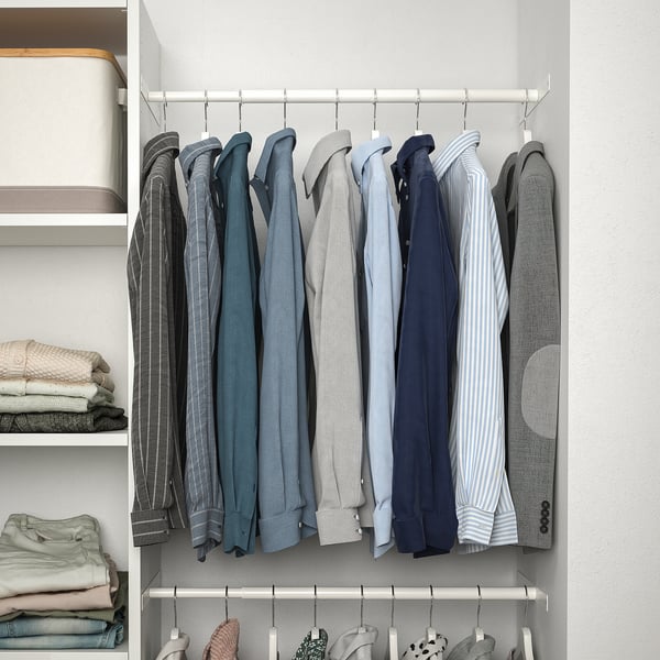 A well-organized closet with a hanging rod system displaying various suits and blazers. Shelves on the side hold neatly folded clothes.