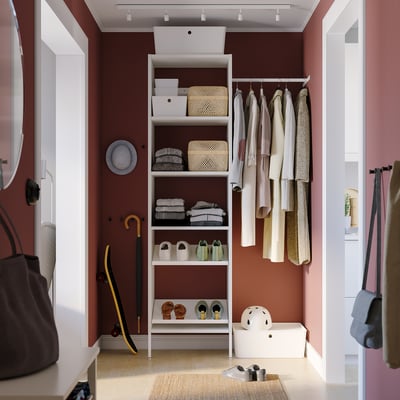 White storage closet with shelves, hanging rail, skateboard, and helmet.