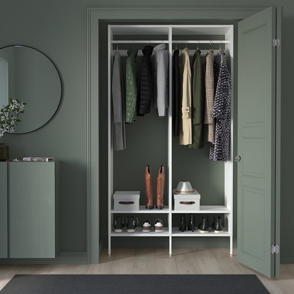 White AURDAL closet with adjustable rails, shelves, and bins. Green walls, wood floors, and a mirror. Customizable storage.