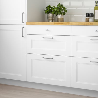 AXSTAD white kitchen drawers, modern design with chrome handles and plants.