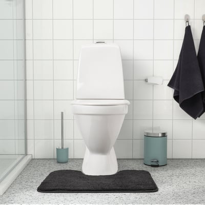 Modern bathroom with white toilet on dark mat. Blue accessories, minimalistic.