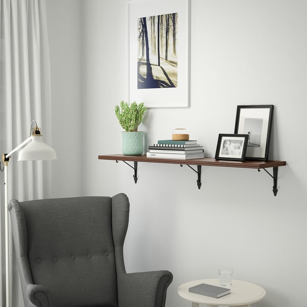 Cosy reading nook with armchair, side table, and wall shelf with books and decor.