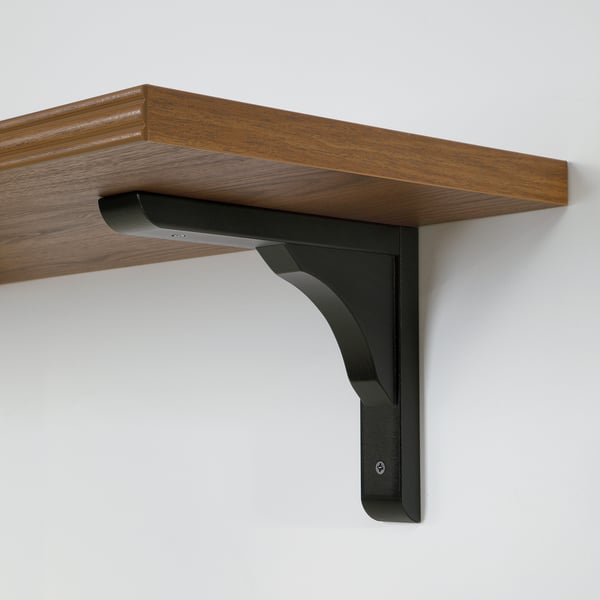 Wall-mounted wooden shelf with dark metal brackets, securely fixed to a light-colored wall.