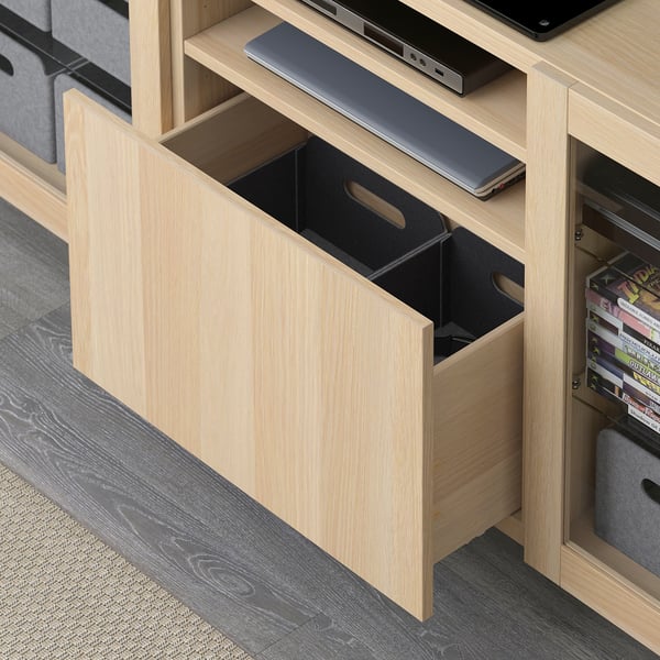 Wooden desk with open drawer containing bins, a laptop, and books, optimised for organisation.