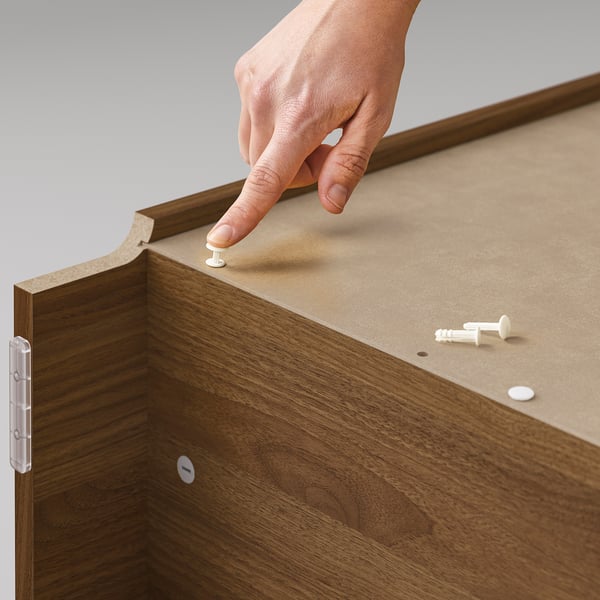 Person assembling wooden BILLY furniture, brown, using screws and hinges.