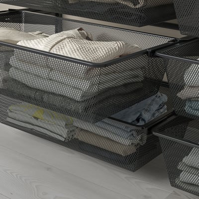 Mesh baskets in drawers hold folded clothes, allowing air circulation. Part of a modular wall-mounted storage system.