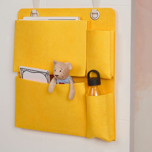 Yellow BÖNSYRSA organiser on wall with bear, book, and bottle in kids room.