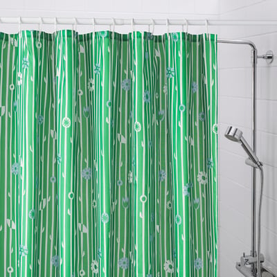 Green shower curtain with small flowers, fully covering bath area.
