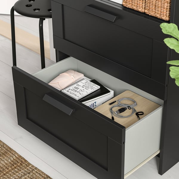 Black storage unit with open drawer showing books, clamp, and cables. Adjustable shelves.