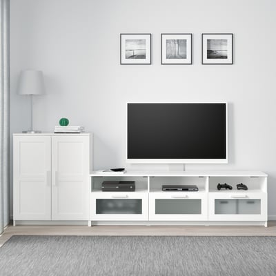 Modern living room with white BRIMNES tv bench and gaming consoles, flanked by cabinets, and three black-and-white photos on grey wall.