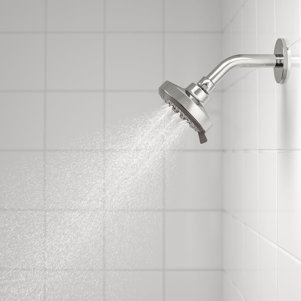 Silver shower head with multiple spray functions, attached to white tiled wall.