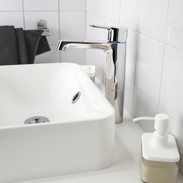 A modern bathroom sink with BROGRUND chrome mixer tap and soap dispenser.