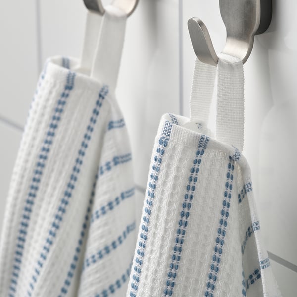 Two white towels with blue stripes hang from silver hooks, one showing waffle texture, the other soft terry side.