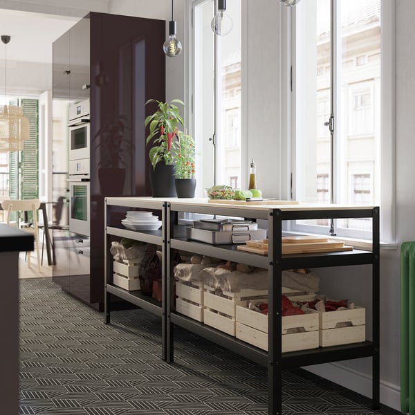 Black metal storage shelf with wooden crates and kitchen items by window.