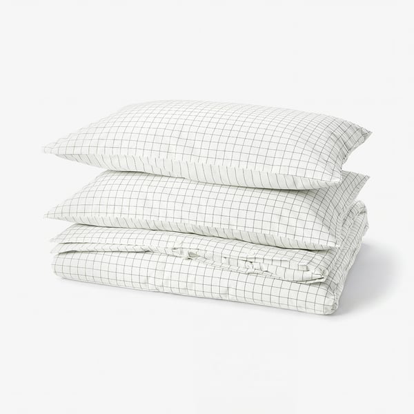 Folded white and anthracite chequered duvet cover set with striped reverse side. Cotton fabric with stitched patterns.