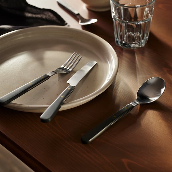 DOFTSKÖLD cutlery set, matte grey. Sleek design with gold accents, fits neatly on a plate, slightly larger than typical cutlery.
