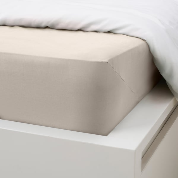 A neatly made bed with a beige fitted sheet on a white bed frame. The sheet appears smooth and well-fitted, suggesting comfort and quality.