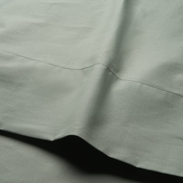 Close-up of DVALA bedsheet in soft grey-green, showcasing smooth texture and fine stitching.