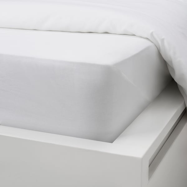 A fitted white cotton sheet, visibly stretched on a bed, showcasing its snug fit and natural, breathable material.
