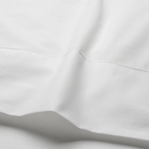 Close-up of crisp, white cotton sheets. Shows fine stitching and smooth texture, highlighting quality and softness for comfortable sleeping.