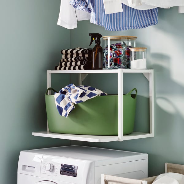 Thrift store shelf with white washer, green basket, jars, and towels.