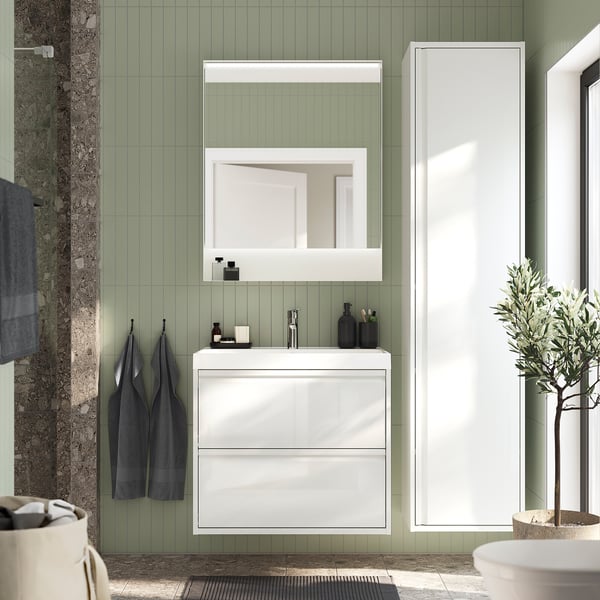 Modern bathroom: FAXÄLVEN mirror, green walls, white cabinet, dark towels, plant, and integrated lighting.