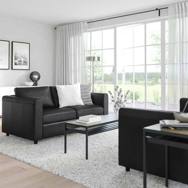 Modern living room with FINNALA sectional sofa, white pillows, coffee table, large windows, and plants.