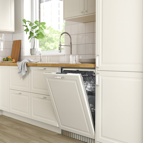 Modern kitchen with open white FLÅBODA dishwasher, silver tap, wooden countertop, and green plant.